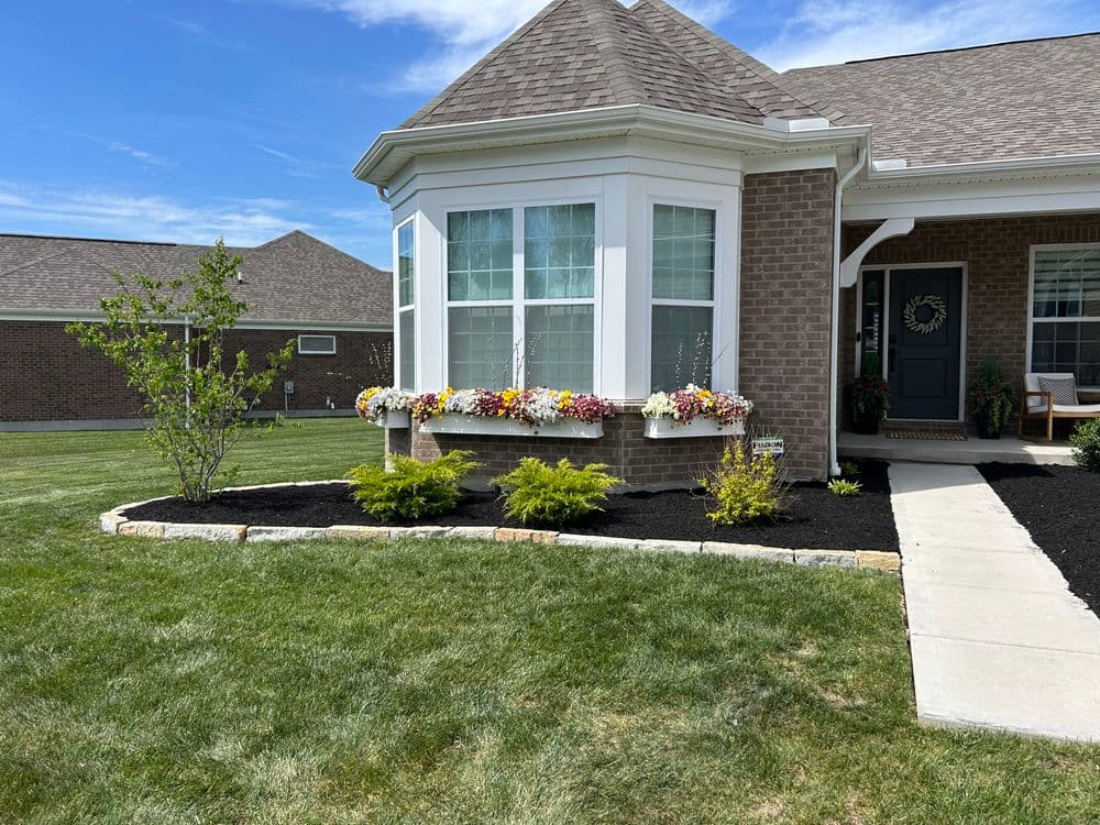 Charming house with flower boxes, landscaping, and blue sky in a suburban setting.