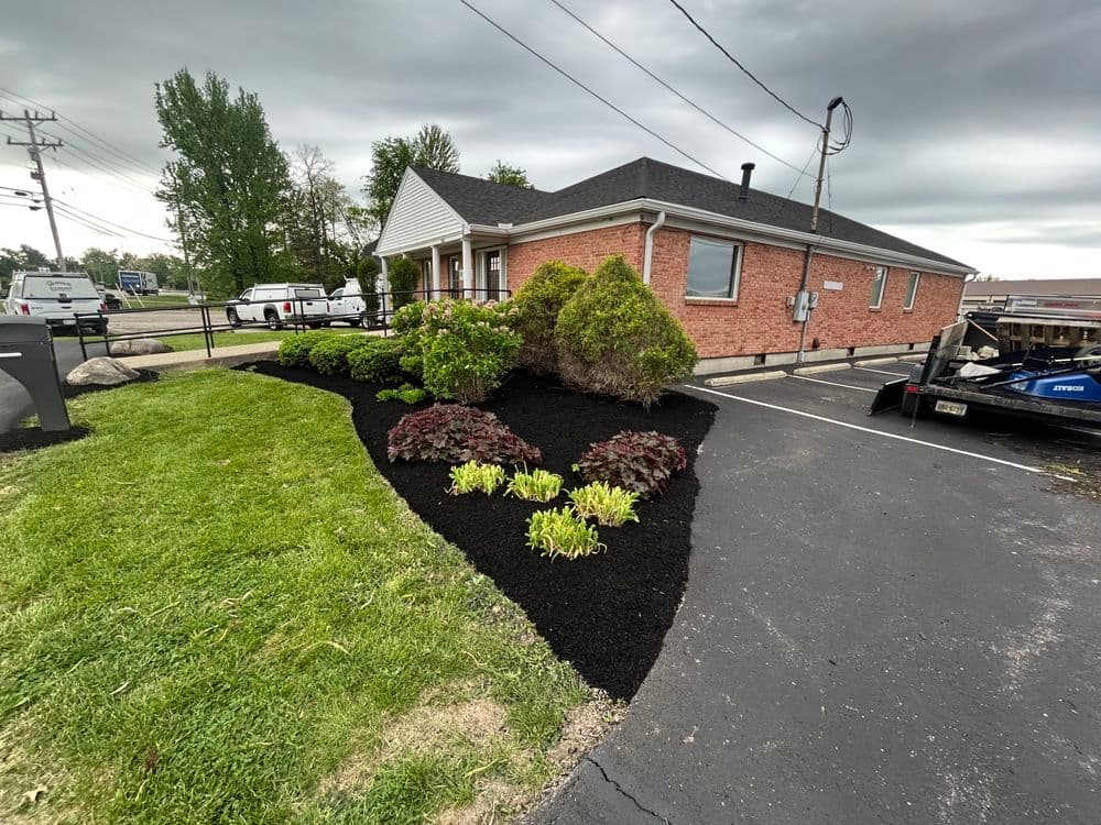 Landscaped office building with blooming plants and freshly applied black mulch.