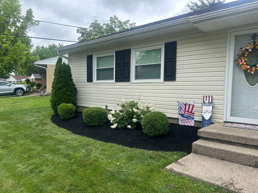 Front yard with manicured shrubs, flower beds, and a welcoming entrance to a home.