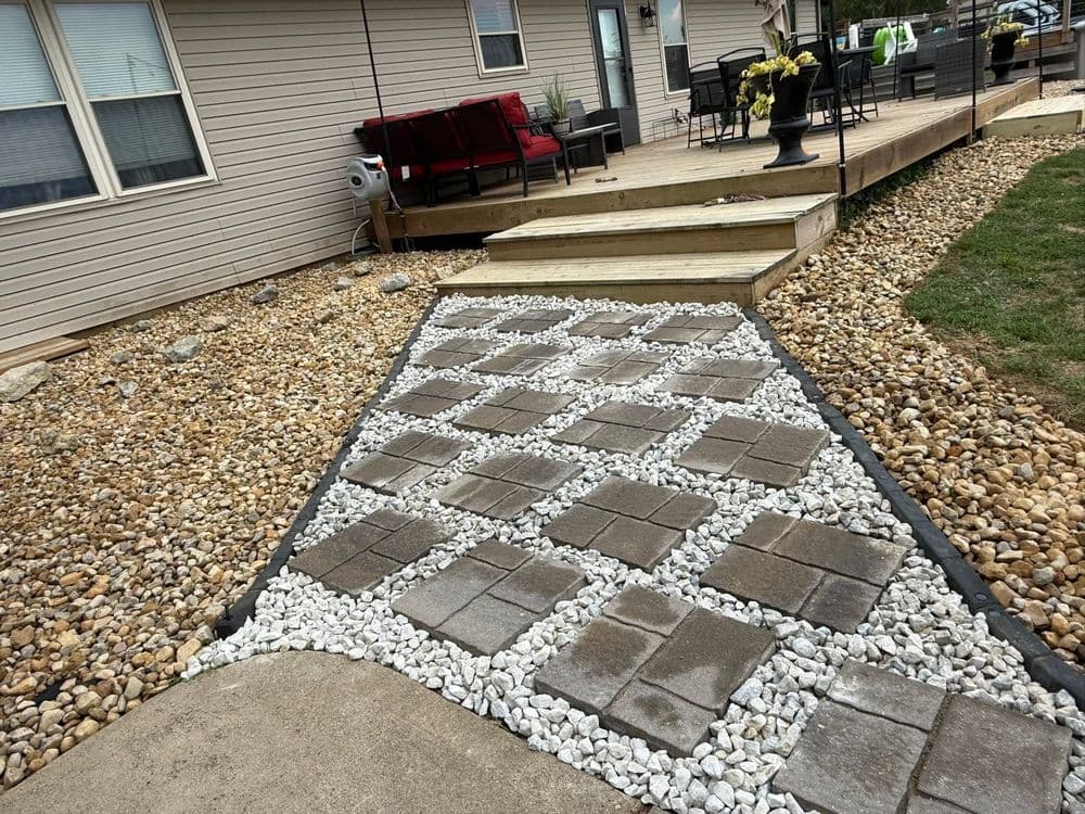 Landscape path with concrete pavers, gravel, and wooden deck, enhancing outdoor space.